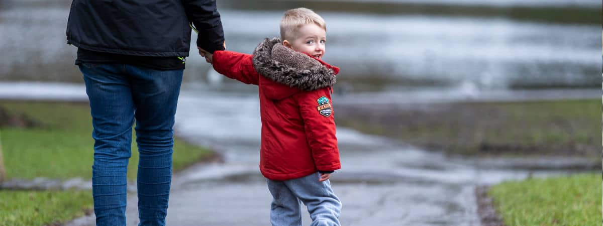 Young boy with person holding his hand in the rain